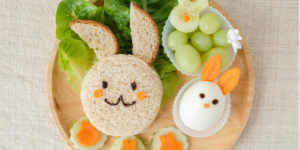 Easter Meal: Lettuce, Bread, Apple, Carrot, Egg, Grapes and Melon. All arranged in bunny shapes.