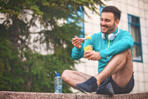 Young man smiling eating pineapple in his running gear